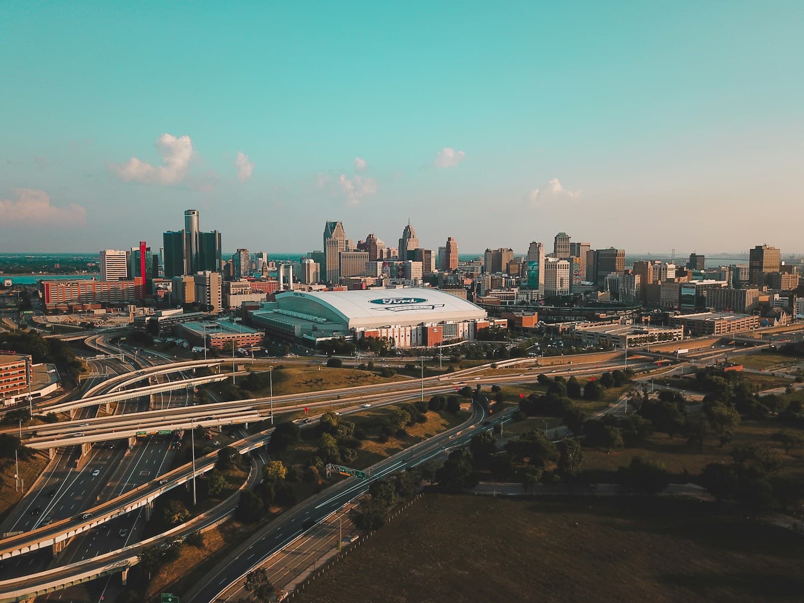 Aerial view of city skyline with downtown buildings, stadium, and highway interchanges at sunset