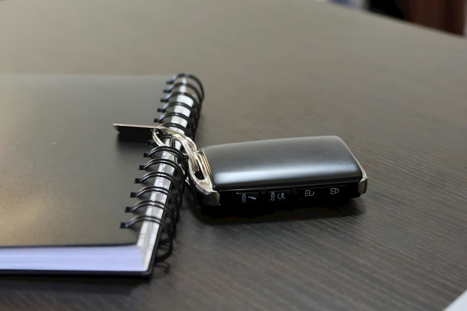 Black smartphone placed on open spiral notebook on wooden desk