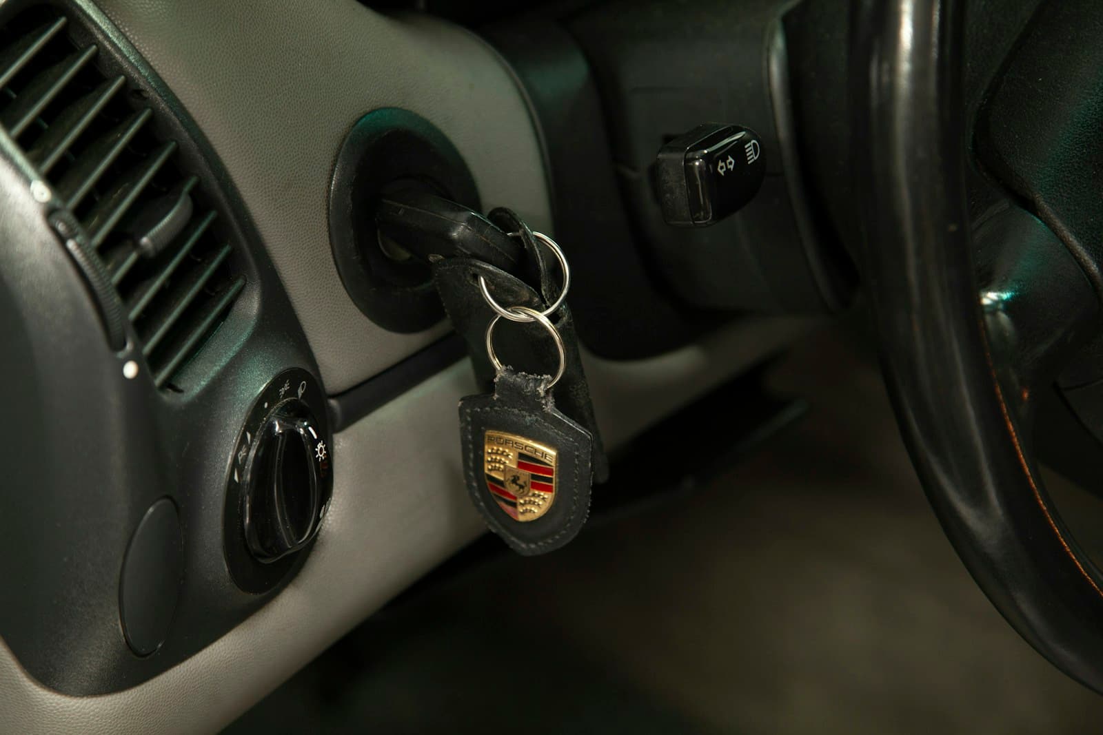 Car keys with Porsche logo keychain in ignition of luxury vehicle interior