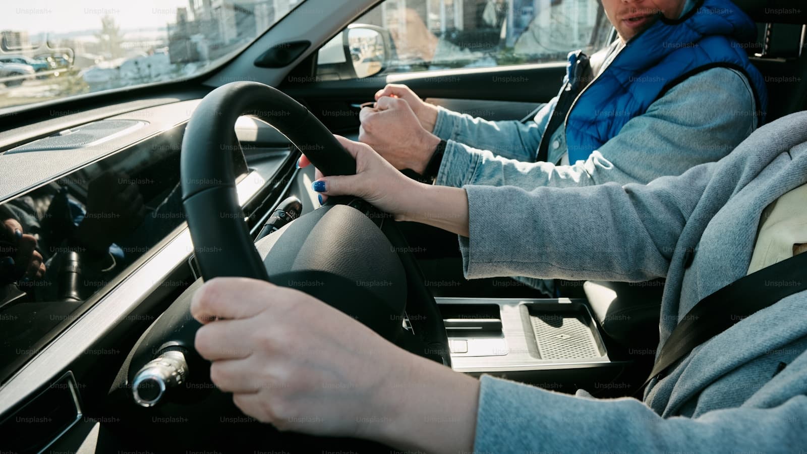 Driver in a light gray sweatshirt at the wheel with a passenger alongside
