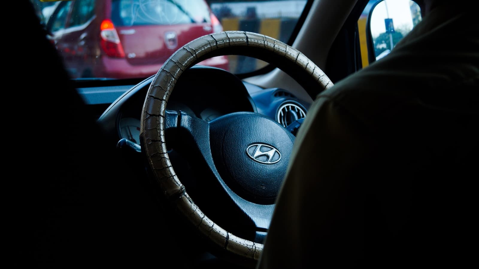 Interior view of Hyundai car steering wheel with logo visible, other cars seen through windshield