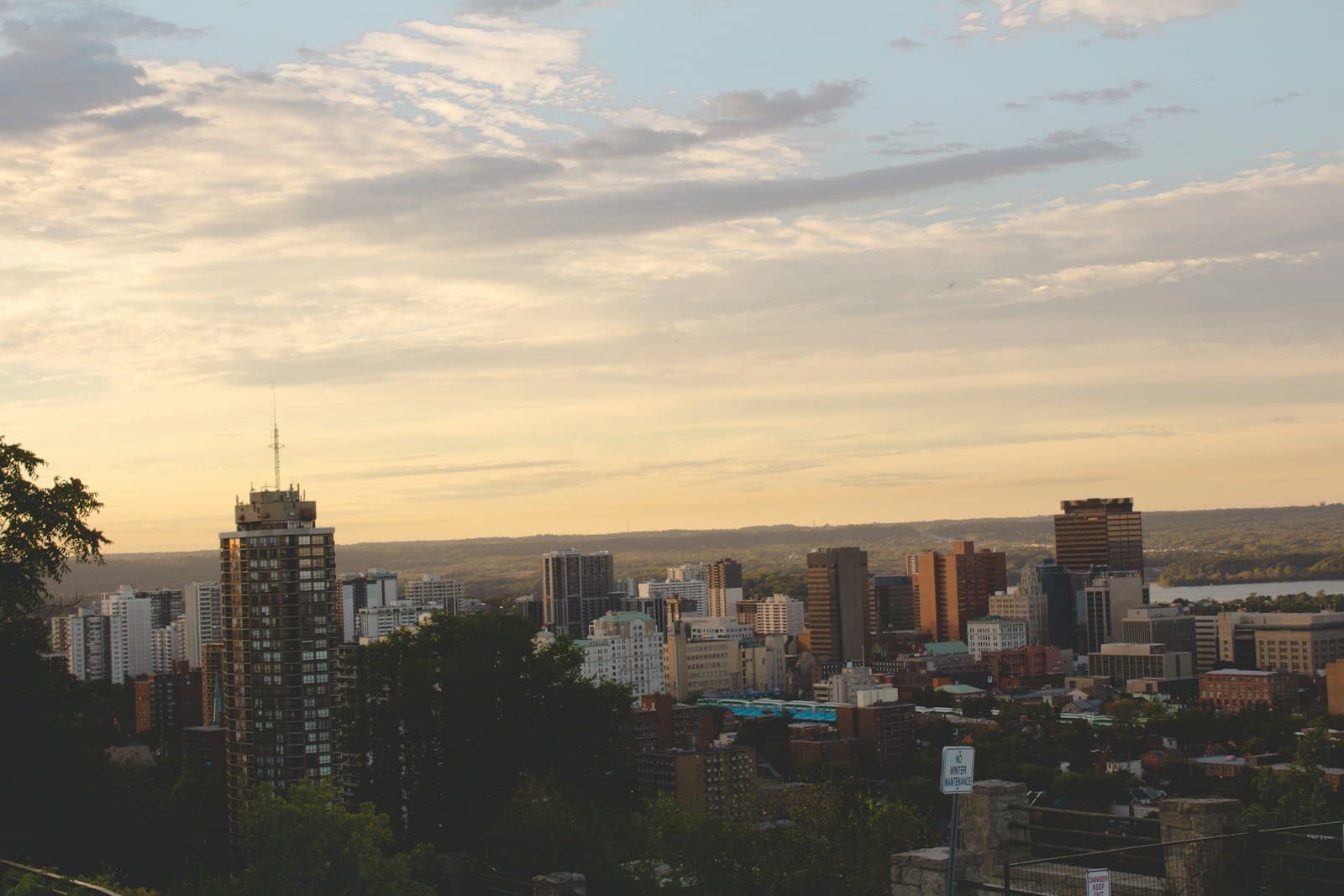 City skyline at sunset with tall buildings and dramatic cloudy sky in warm golden light