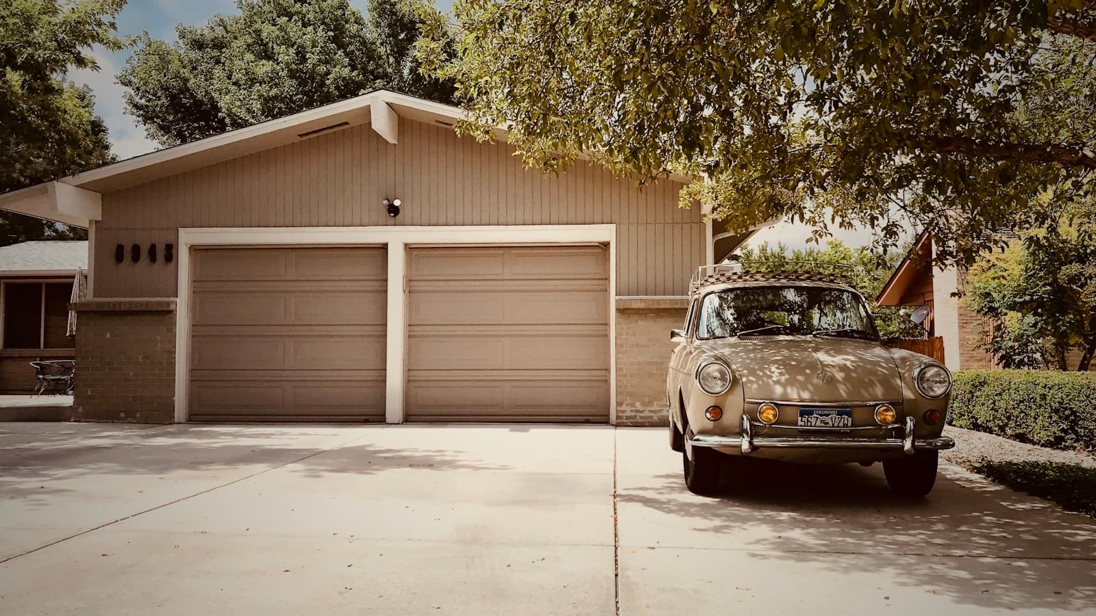 Vintage Volkswagen Beetle parked in the driveway of a suburban home with a two-car garage