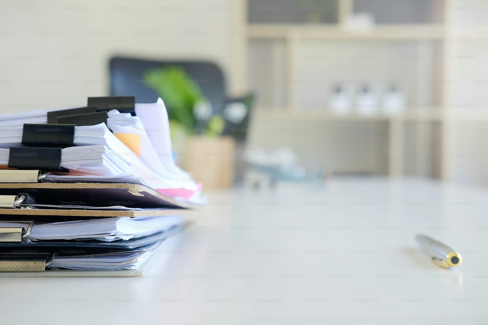 Stack of office documents and papers on white desk in modern office setting